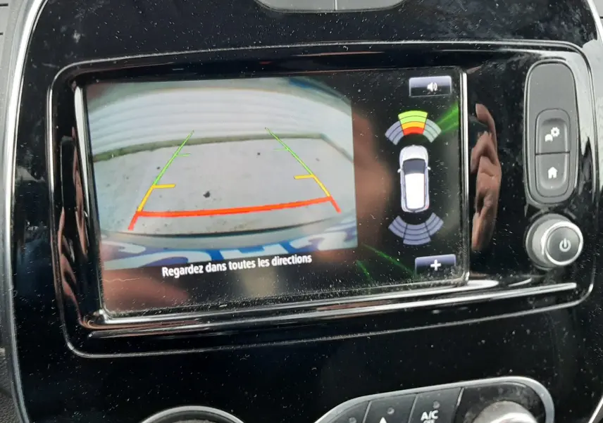 Vue rapprochée de l'écran multimédia du Renault Captur 2017 montrant la caméra de recul avec guidage et capteurs d'aide au stationnement.