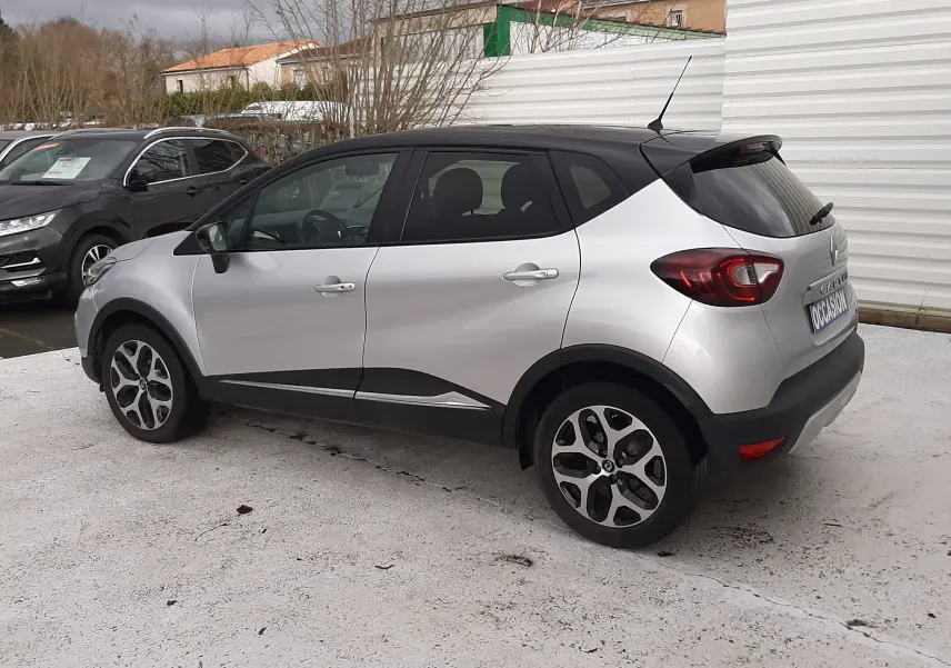 Renault Captur 2017 gris avec toit noir, vue de profil côté gauche, jantes alliage et détails noirs contrastants.