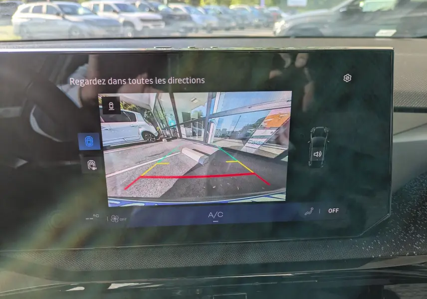 Écran central affichant la caméra de recul d'une Renault Clio VI TCe 115ch Techno, vue arrière avec lignes de guidage colorées.