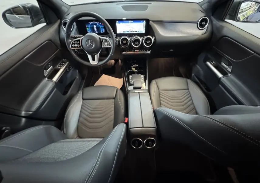 Vue intérieure avant du Mercedes GLA 250 e Business Line 2023, sièges cuir noirs et tableau de bord digital avec écran tactile central.