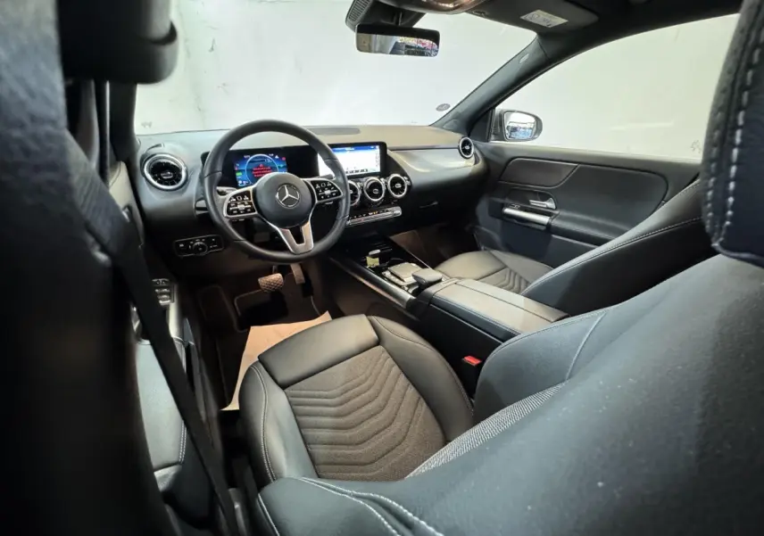 Vue intérieure côté conducteur du Mercedes GLA 250 e Business Line 2023, avec tableau de bord numérique et sièges noirs.