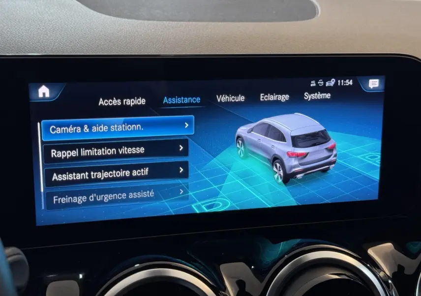 Écran tactile central montrant l'assistance au stationnement avec vue 3/4 arrière d'un Mercedes GLA gris foncé.