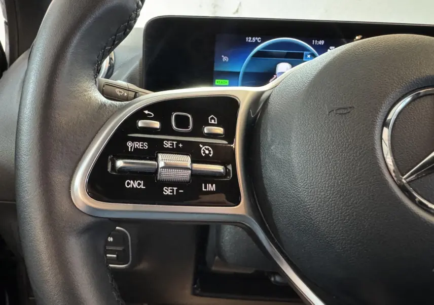 Gros plan sur les commandes gauche du volant cuir noir du Mercedes GLA 250 e Business Line 2023 avec affichage numérique.