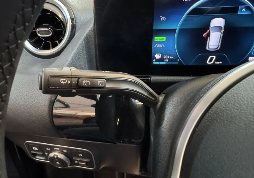 Gros plan sur la commande d’essuie-glace à gauche du volant d’un Mercedes GLA 250 e gris foncé avec tableau de bord numérique.
