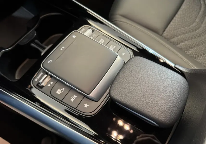 Gros plan sur la console centrale noire avec pavé tactile et accoudoir en cuir gris du Mercedes GLA 250 e Business Line 2023.