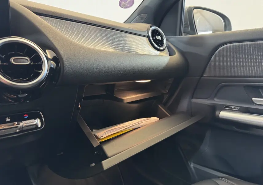 Intérieur du Mercedes GLA 250 e Business Line 2023, vue côté passager avec boîte à gants ouverte et détails noirs et argentés.