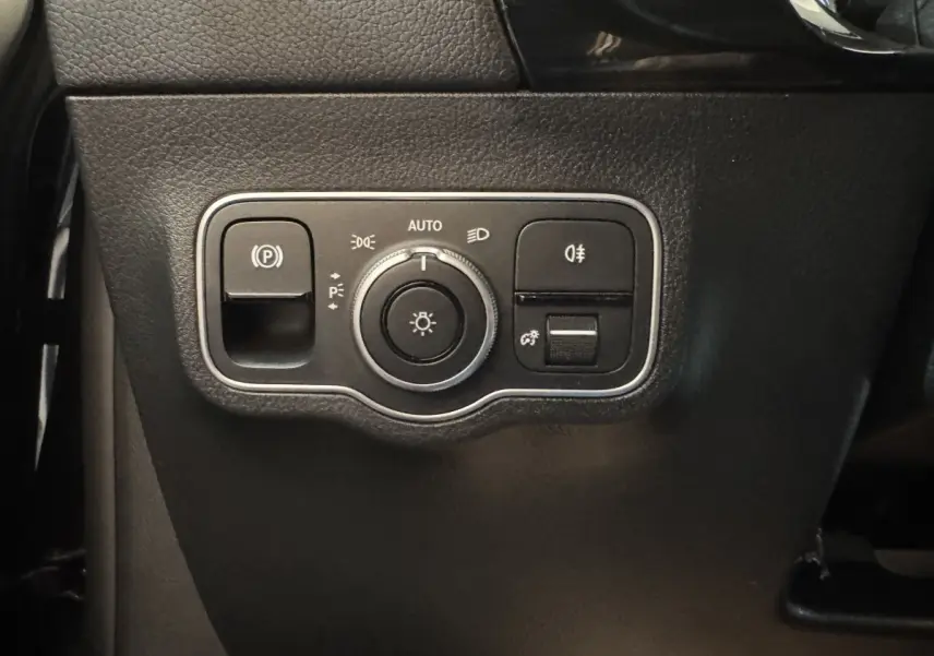 Gros plan sur le panneau de commande des phares et du frein à main électrique, intérieur noir du Mercedes GLA 250 e.