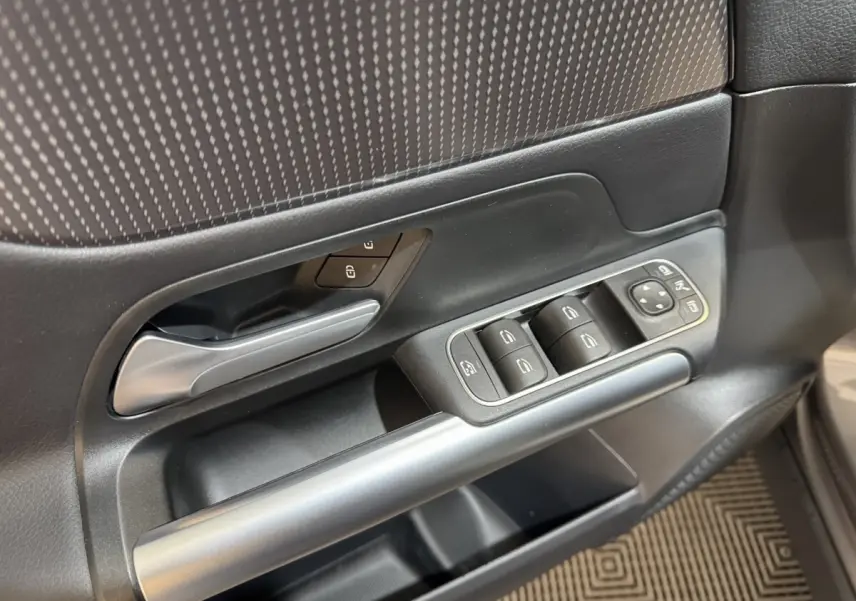 Gros plan sur la porte côté gauche gris foncé du Mercedes GLA 250 e avec commandes des vitres et poignée argentée.