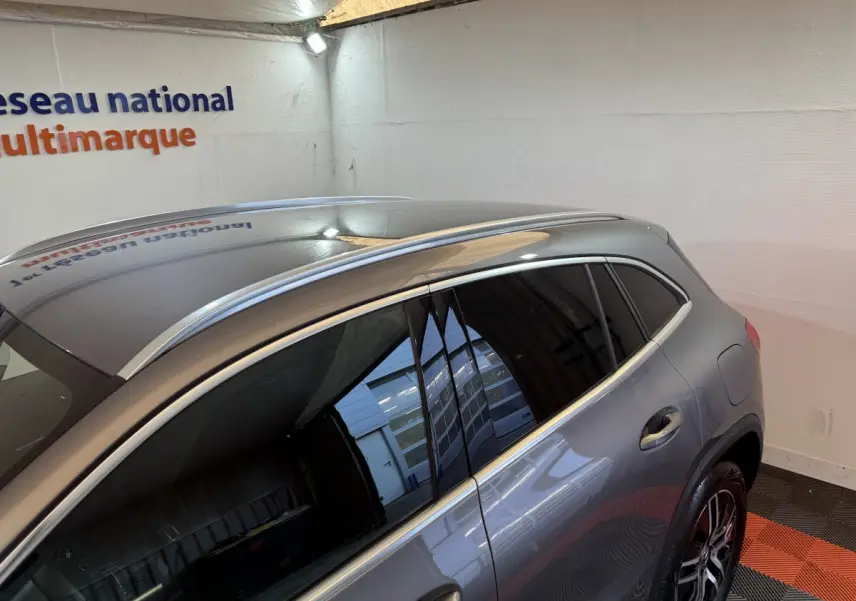 Vue 3/4 arrière droite d’un Mercedes GLA 250 e Business Line gris foncé avec vitres teintées et barres de toit chromées.