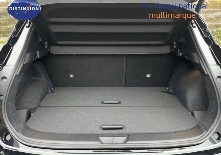 Coffre ouvert vu de l'arrière d'un Nissan Qashqai noir perle métal avec plancher de chargement plat et compartiments dissimulés.