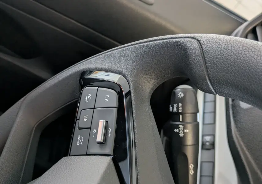 Gros plan sur les commandes au volant noir du Citroën Jumpy cabine approfondie 2025, côté gauche, avec boutons multifonctions.