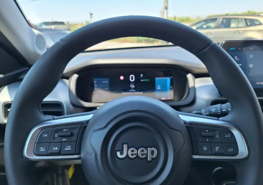 Vue rapprochée du volant noir du Jeep Avenger électrique 2025, avec commandes intégrées et tableau de bord numérique.