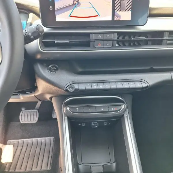 Vue intérieure du tableau de bord du Jeep Avenger électrique blanc, avec écran tactile affichant la caméra de recul et console centrale moderne.