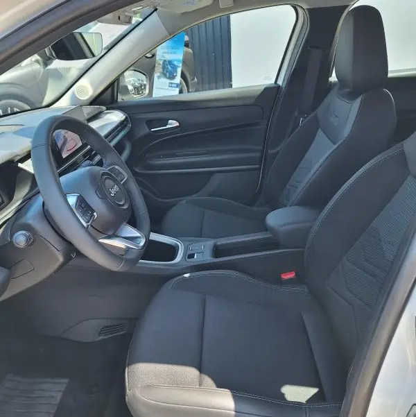 Vue intérieure côté conducteur du Jeep Avenger électrique 2025 avec sièges noirs et volant multifonction.