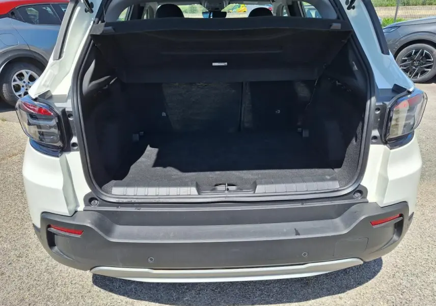 Vue arrière du coffre ouvert d'un Jeep Avenger électrique blanc, mettant en valeur l'espace de chargement.