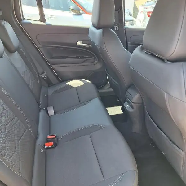 Vue intérieure des sièges arrière en tissu noir du Jeep Avenger électrique blanc, avec ceinture de sécurité et porte arrière visible.