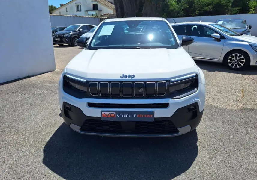 Vue de face d'un Jeep Avenger électrique blanc 2025 avec calandre noire et jantes alliage 17 pouces.