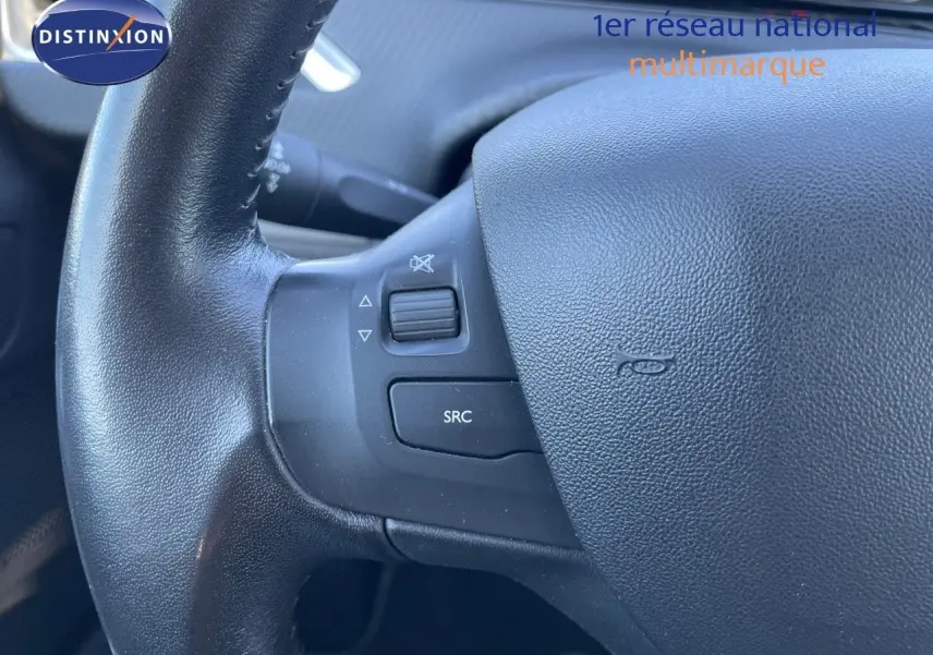Gros plan sur le volant noir du Peugeot 2008 blanc, montrant les commandes audio intégrées à gauche.