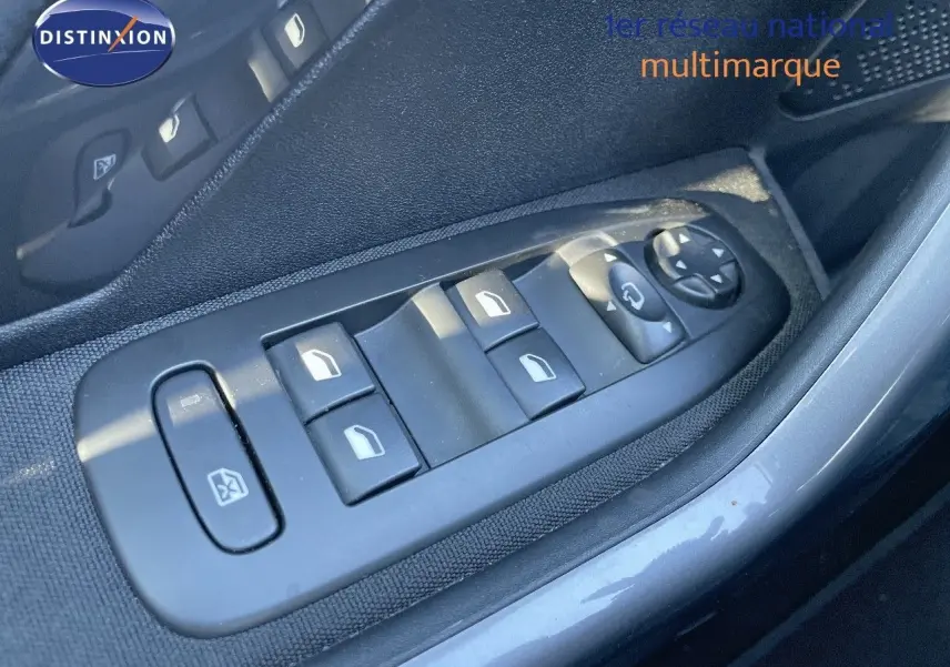 Gros plan sur les commandes des vitres électriques côté gauche d'une Peugeot 2008 blanche, version 2017.