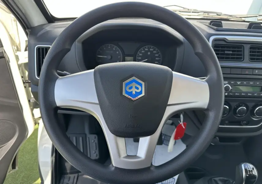 Vue intérieure centrée sur le volant noir et argenté avec logo Piaggio, tableau de bord et levier de vitesses manuelle visibles.