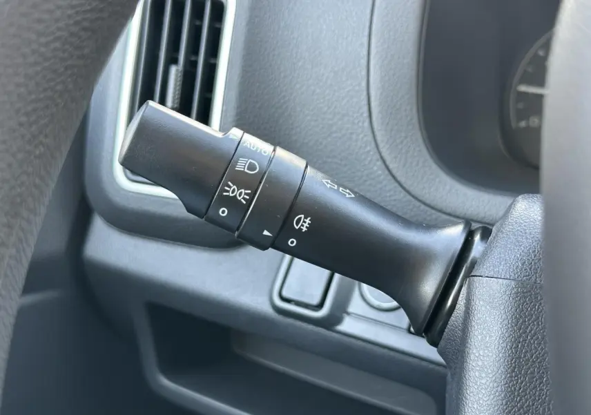 Gros plan sur le commodo d'éclairage noir dans l'habitacle du Piaggio Porter blanc 2024.