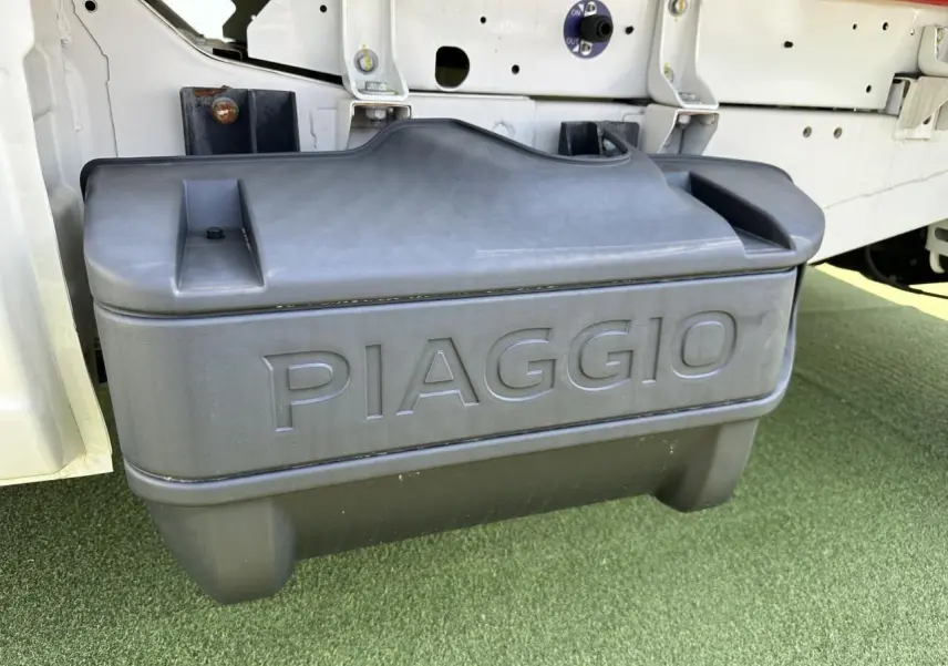 Gros plan sur le réservoir GPL noir marqué PIAGGIO sous la benne blanche du Porter NP6 côté gauche.
