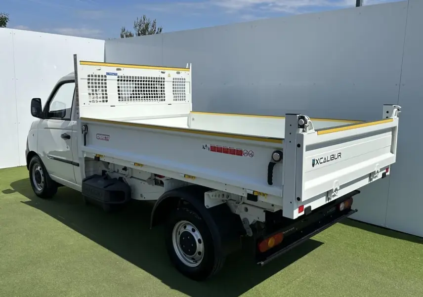 Vue 3/4 arrière droite du Piaggio Porter blanc avec benne longue et ridelle Excalibur sur fond extérieur.