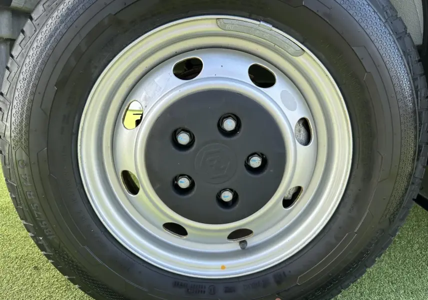 Gros plan sur la roue acier avec logo Piaggio au centre du camion blanc Porter NP6 2024.