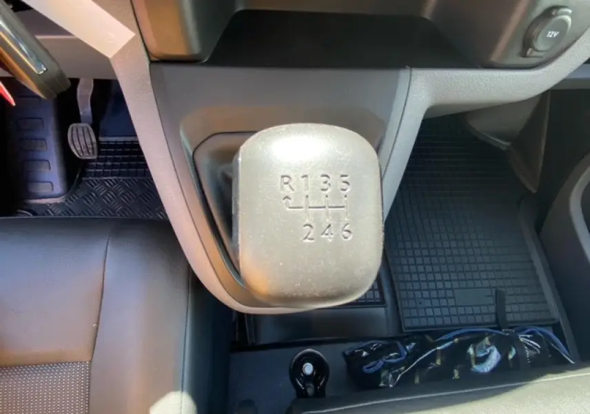 Vue intérieure rapprochée du levier de vitesses manuel du FIAT Scudo Fourgon blanc, avec sièges en cuir noir.