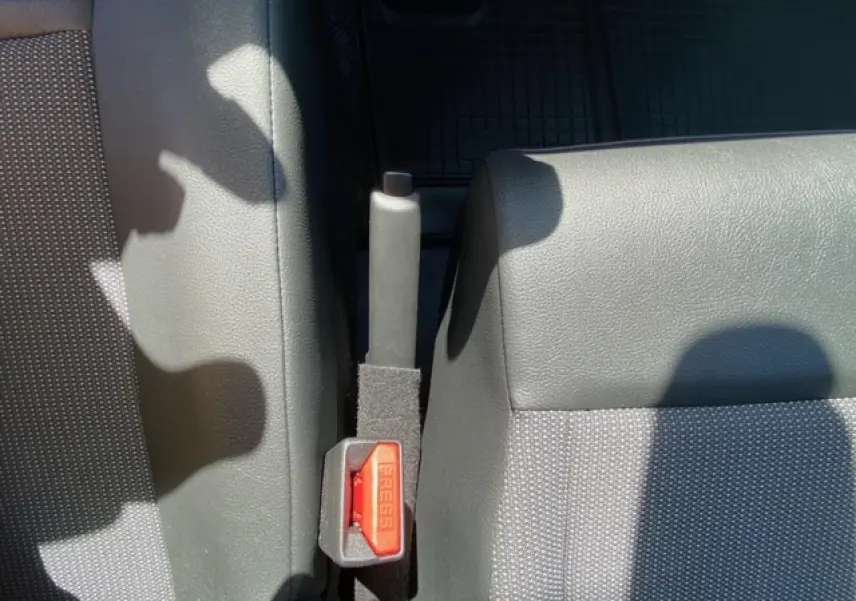 Gros plan sur la poignée de frein à main et la ceinture de sécurité entre les sièges avant gris du Fiat Scudo Fourgon blanc.