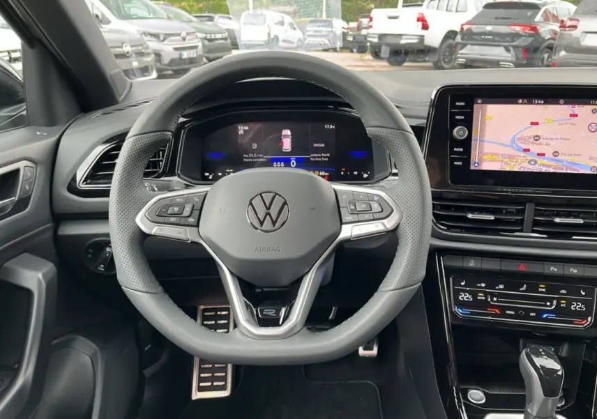 Vue intérieure centrée sur le volant multifonction du Volkswagen T-Roc R-Line Black 2025 avec écran digital et navigation.