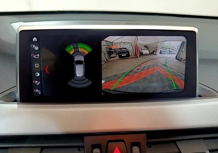 Écran multimédia affichant la caméra de recul et les capteurs de distance du BMW X1 noir, vue intérieure du tableau de bord.
