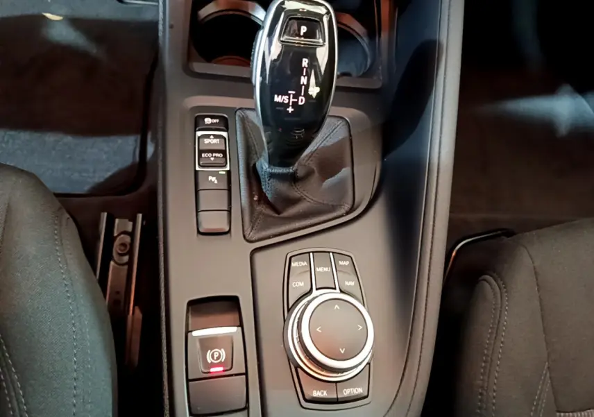 Vue rapprochée de la console centrale noire du BMW X1 2021, avec levier de vitesse automatique et molette de contrôle.