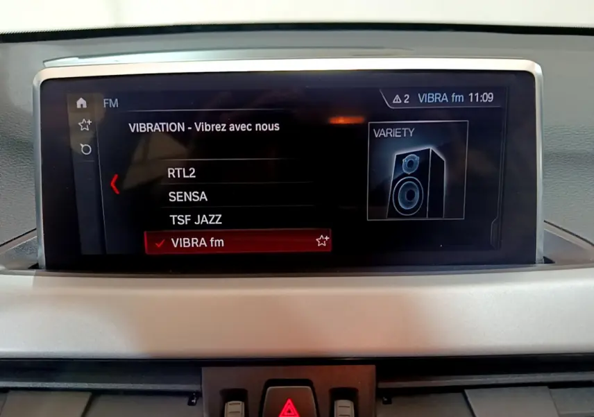 Écran multimédia du tableau de bord de la BMW X1 sDrive16d Lounge 2021 affichant les stations radio FM.