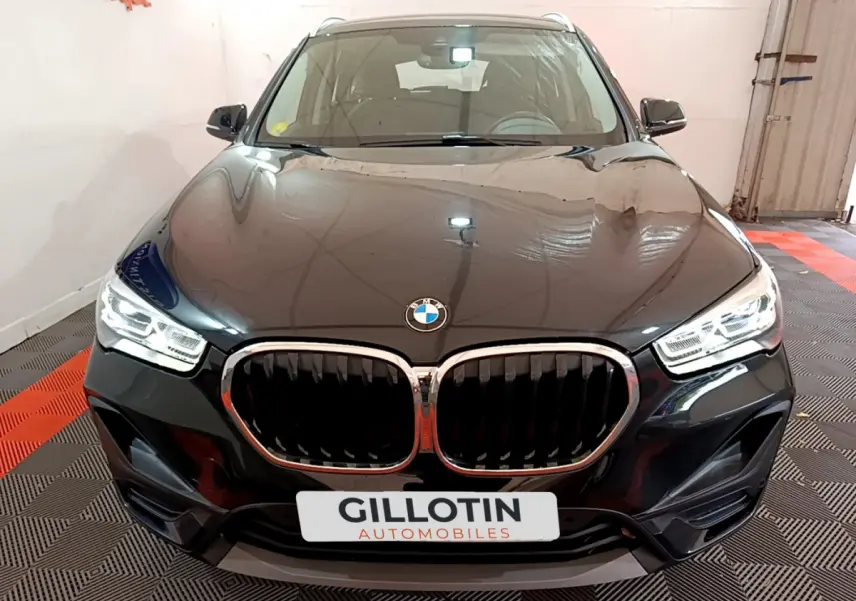 Vue avant d’un BMW X1 sDrive16d Lounge noir avec calandre double haricot et phares LED allumés.