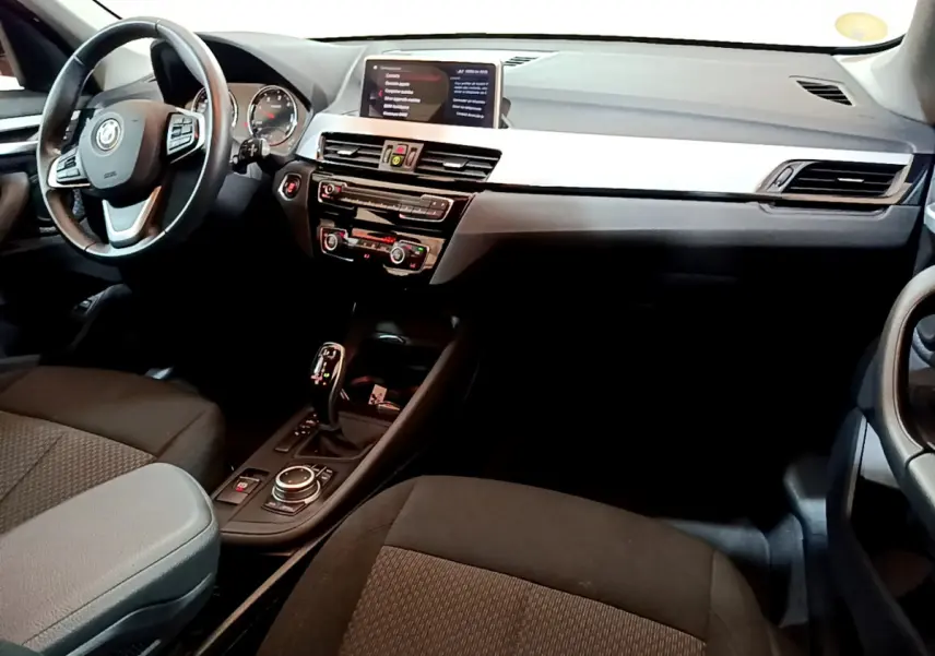Intérieur noir de BMW X1 sDrive16d 2021 vu côté conducteur, avec tableau de bord moderne et écran central.