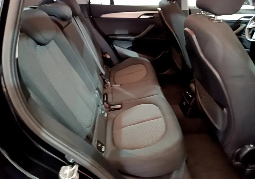 Vue intérieure côté gauche des sièges arrière du BMW X1 noir, montrant les assises en tissu et les dossiers avant.