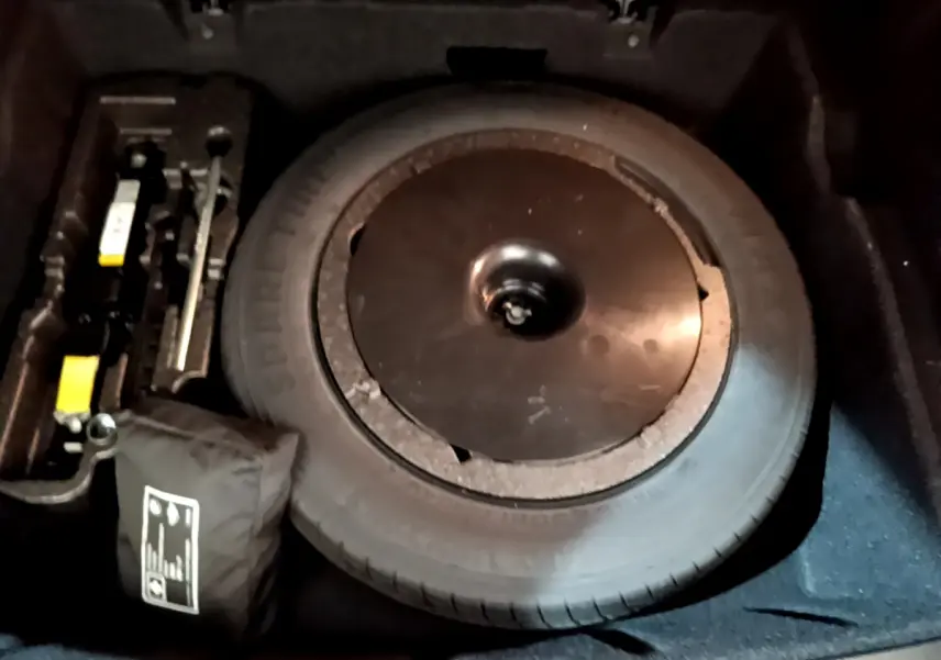 Vue rapprochée de la roue de secours et des outils dans le coffre du BMW X1 sDrive16d noir de 2021.