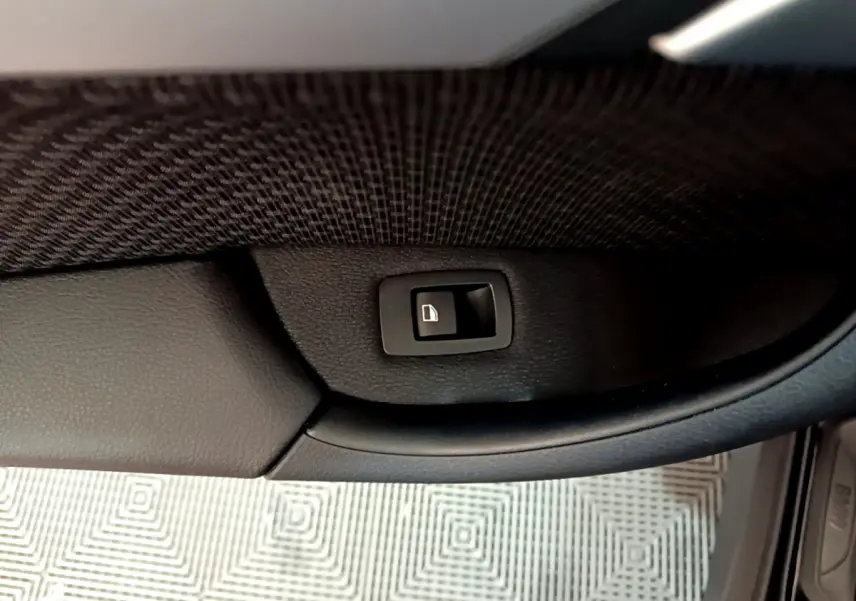 Bouton de verrouillage de porte noir sur panneau intérieur en cuir noir, vue rapprochée côté conducteur d'un BMW X1 noir.