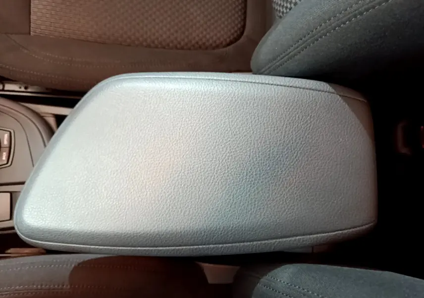 Gros plan sur l'accoudoir central en cuir gris du BMW X1 sDrive16d Lounge DKG7, intérieur noir.