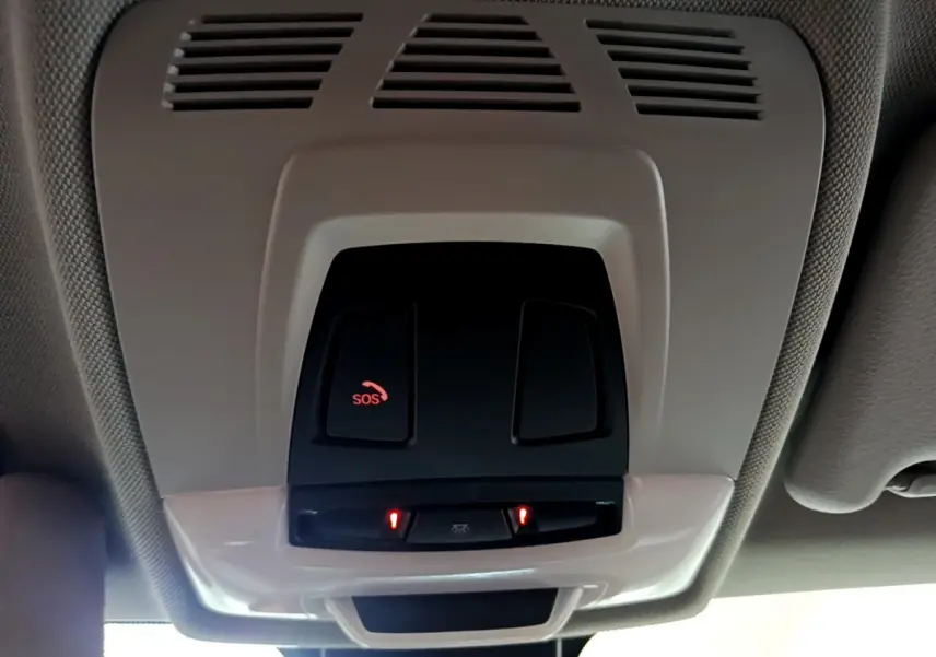 Vue intérieure en gros plan du plafonnier noir avec bouton SOS rouge allumé dans un BMW X1 noir 2021.