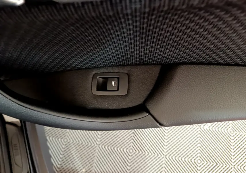 Bouton de fermeture électrique du coffre sur panneau intérieur noir d’une BMW X1 sDrive16d Lounge 2021.