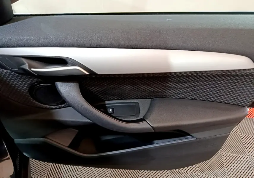 Gros plan sur la porte intérieure côté gauche de la BMW X1 sDrive16d Lounge 2021, avec insert gris et tissu texturé noir.