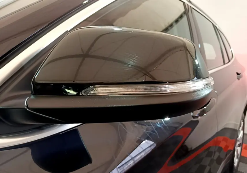 Gros plan sur le rétroviseur côté gauche noir brillant d’un BMW X1 sDrive16d Lounge DKG7 2021.