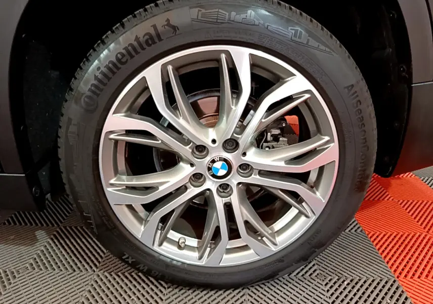 Vue rapprochée sur la roue arrière droite d’un BMW X1 noir, mettant en valeur le pneu Continental AllSeasonContact.