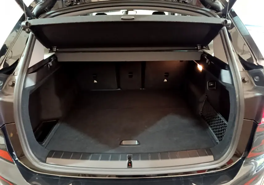 Coffre ouvert vu de l'arrière d'un BMW X1 noir 2021, espace de chargement spacieux avec cache-bagages relevé.