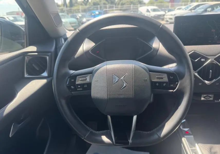 Vue centrée sur le volant noir du DS3 100 BVM6 Bastille 2024 avec tableau de bord et écran tactile en arrière-plan.