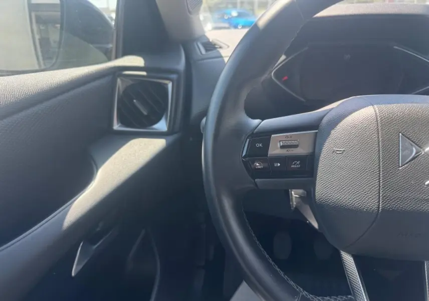 Vue intérieure côté conducteur du DS3 2024 gris, avec volant multifonction et commande d'assistance au pilotage.