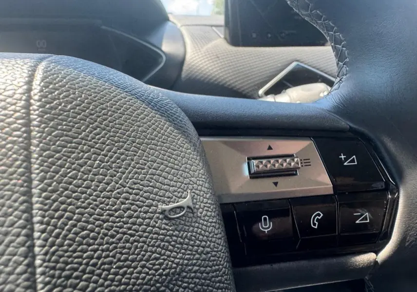 Gros plan sur le volant noir texturé du DS3 100 BVM6 Bastille 2024 avec commandes audio et téléphone intégrées.