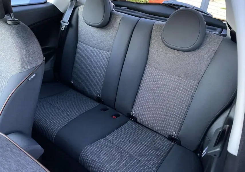 Vue intérieure arrière montrant les sièges arrière gris et noirs du Fiat 500 électrique blanc 2022.